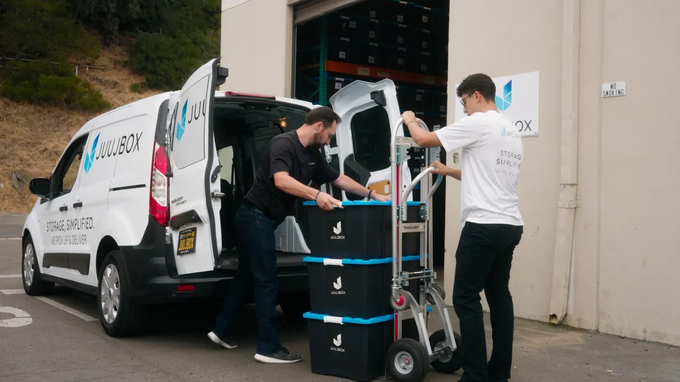 Juujbox crew unloading branded storage totes from a van at the warehouse after a staging