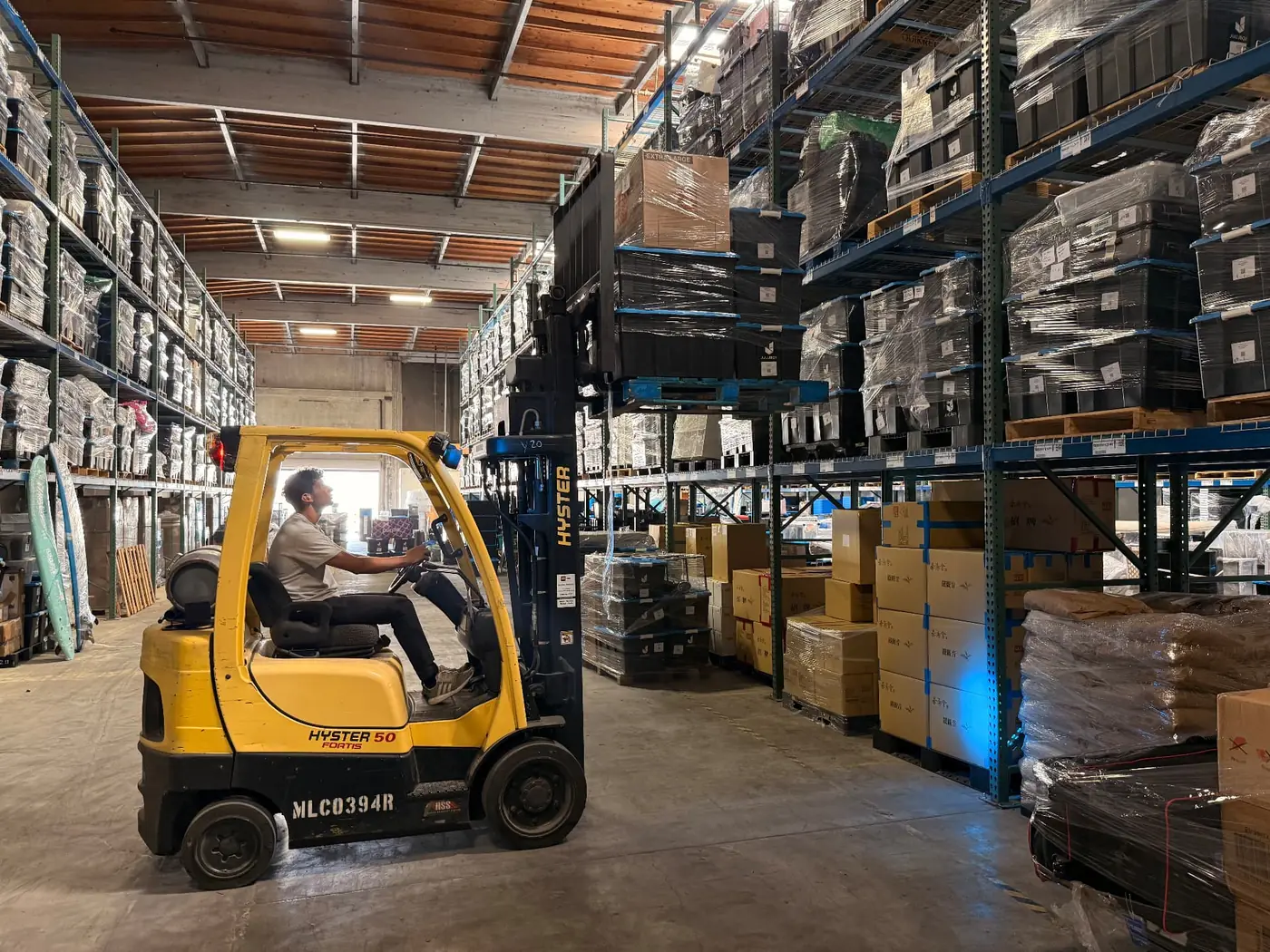 Juujbox team member operating a forklift among pallet racks of stored trade show booths and event materials