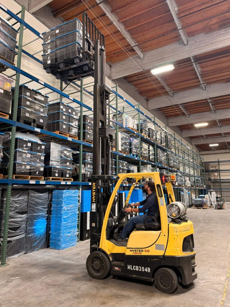 Forklift loading a pallet of stored booth assets onto high pallet racking inside the Juujbox San Diego warehouse